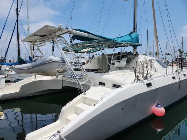 Slide: The Image of 2000 Ocean Cat 49 catamaran docked at marina with blue canopy and dinghy. - 22