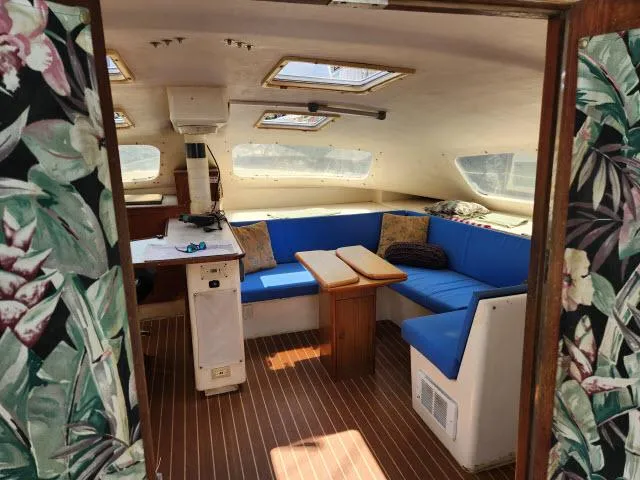Slide: The Image of Interior of 2000 Ocean Cat 49 sailboat with blue seating and wooden table. - 31