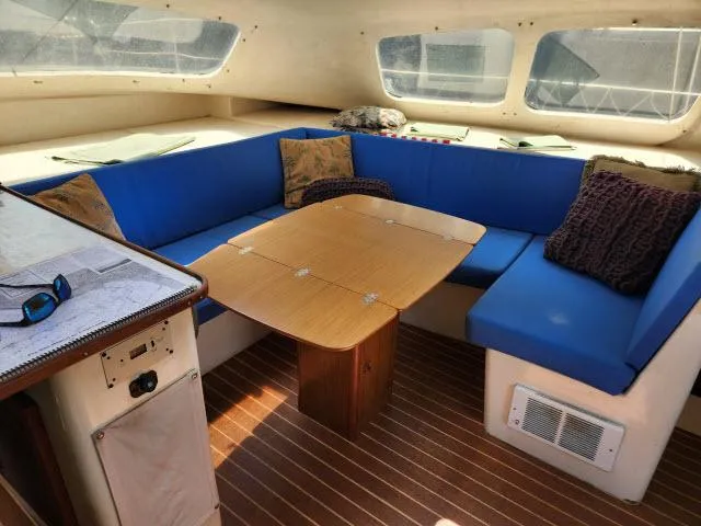 Slide: The Image of Interior of 2000 Ocean Cat 49 catamaran with blue seating and wooden table. - 37