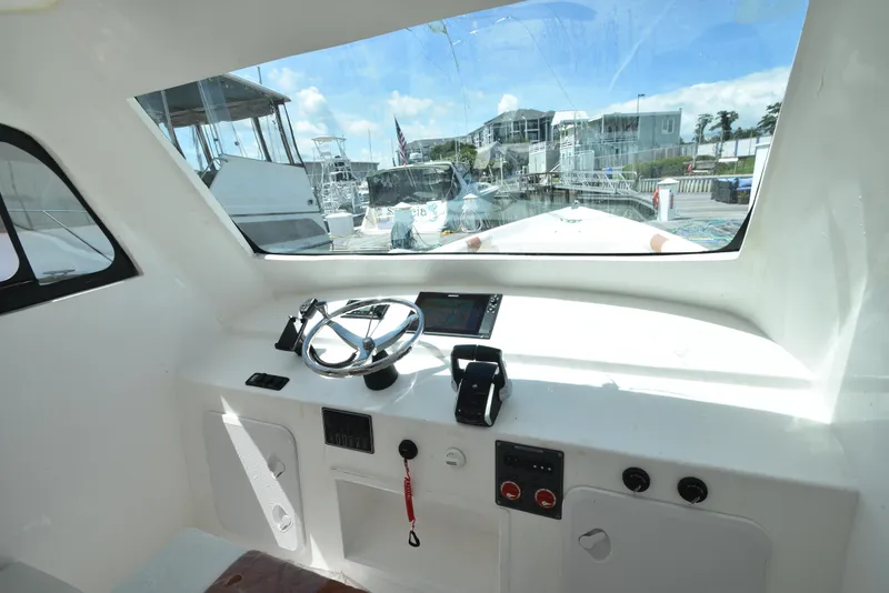 Slide: The Image of Interior helm of 2023 Custom Aljerewy Wave Master boat with steering wheel and navigation controls. - 13