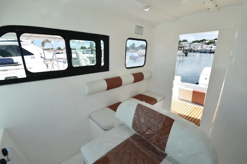 Slide: The Image of Interior of 2023 Custom Aljerewy Wave Master boat with brown and white seating, docked at marina. - 14