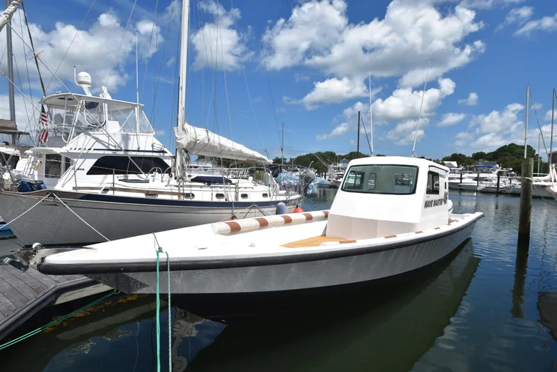 Slide: The Image of Custom 2023 Aljerewy Wave Master boat docked at a marina on a sunny day. - 2