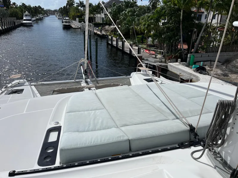 Slide: The Image of Lagoon 55 yacht, 2021 model, docked in a scenic canal with lush greenery. - 11