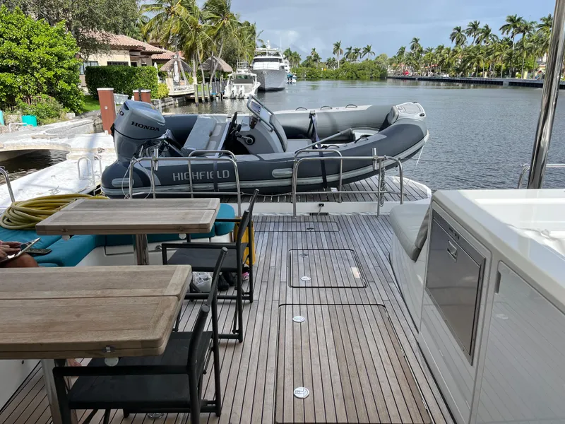 Slide: The Image of Lagoon 55 yacht deck with dining area and inflatable boat, 2021 model. - 15