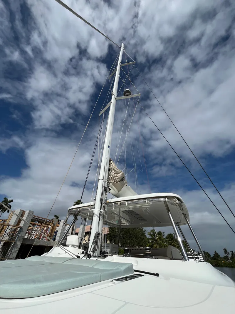 Slide: The Image of Lagoon 55 catamaran, 2021 model, with sails against a partly cloudy sky. - 2