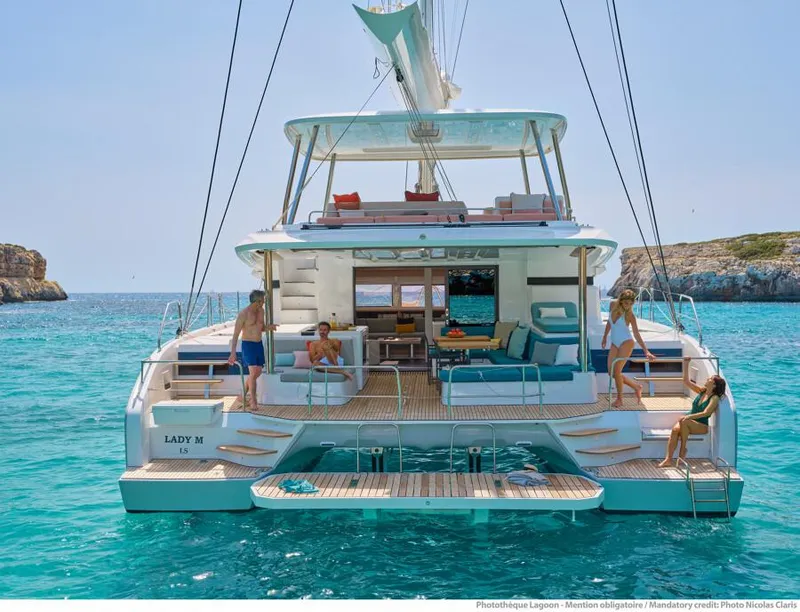 Slide: The Image of Luxury Lagoon 55 yacht 2021 model anchored in clear blue waters with people relaxing. - 5