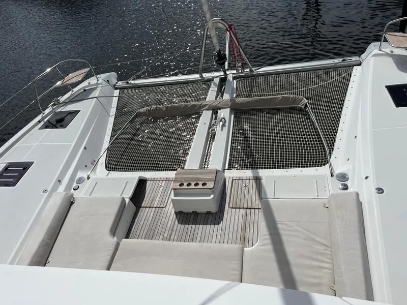 Slide: The Image of Lagoon 55 catamaran deck, 2021 model, featuring spacious seating and netting over water. - 8