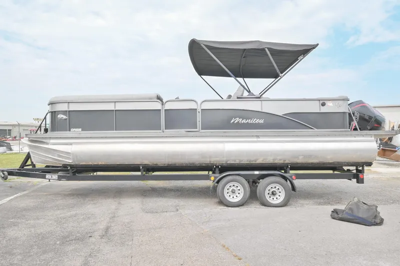 The Image of 2022 Manitou 25 Oasis VP pontoon boat on trailer with canopy, side view. - 0