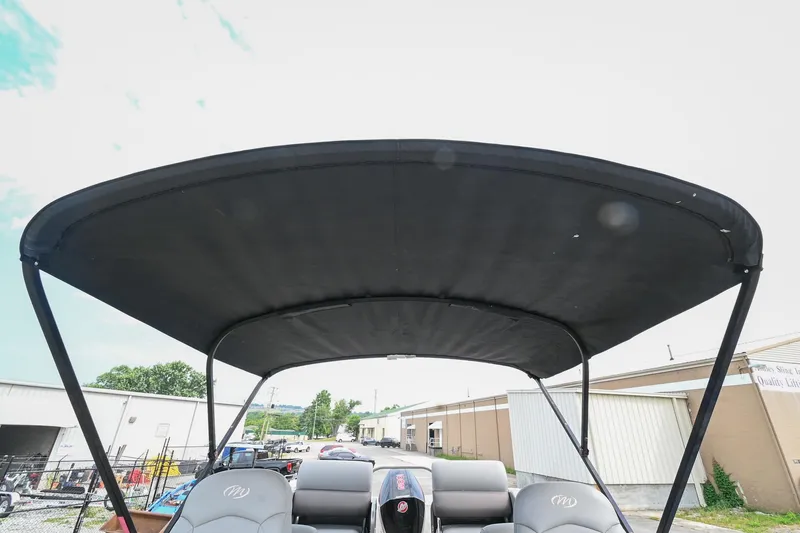 Slide: The Image of 2022 Manitou 25 Oasis VP boat with black canopy, parked outdoors. - 25