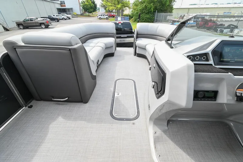 Slide: The Image of 2022 Manitou 25 Oasis VP pontoon boat interior with gray seating and modern dashboard. - 26