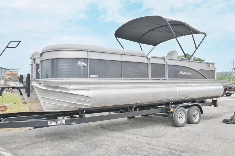 Slide: The Image of 2022 Manitou 25 Oasis VP pontoon boat on trailer with canopy, parked outdoors. - 3