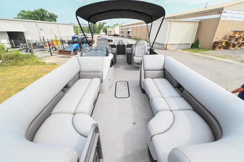 Slide: The Image of 2022 Manitou 25 Oasis VP pontoon boat with spacious seating and canopy, parked outdoors. - 4