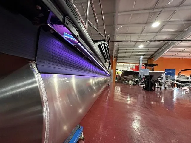 Slide: The Image of 2025 Bennington 24 LXSBA pontoon boat with purple LED lights in showroom. - 30