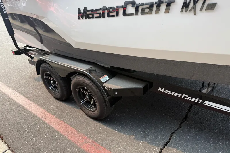 Slide: The Image of 2024 MasterCraft NXT23 boat on trailer, showcasing sleek design and dual wheels. - 10