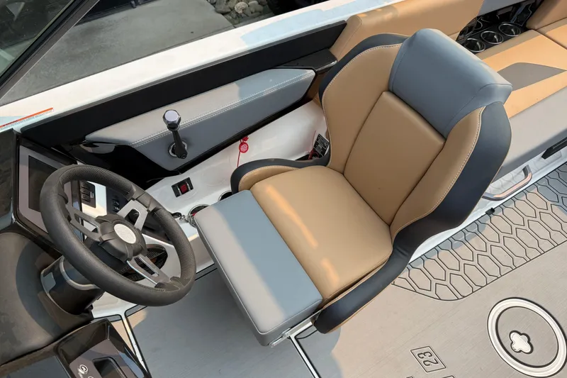 Slide: The Image of 2024 MasterCraft NXT23 boat interior with steering wheel and tan seating. - 15