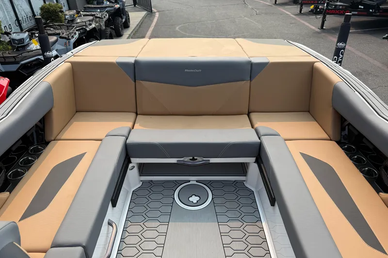 Slide: The Image of 2024 MasterCraft NXT23 boat interior with tan and gray seating, hexagonal floor design. - 18