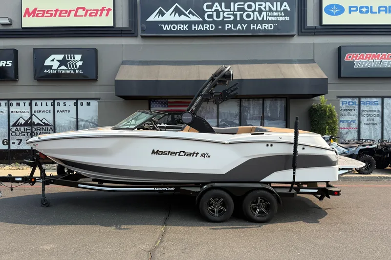 Slide: The Image of 2024 MasterCraft NXT23 boat on trailer outside California Custom showroom. - 2