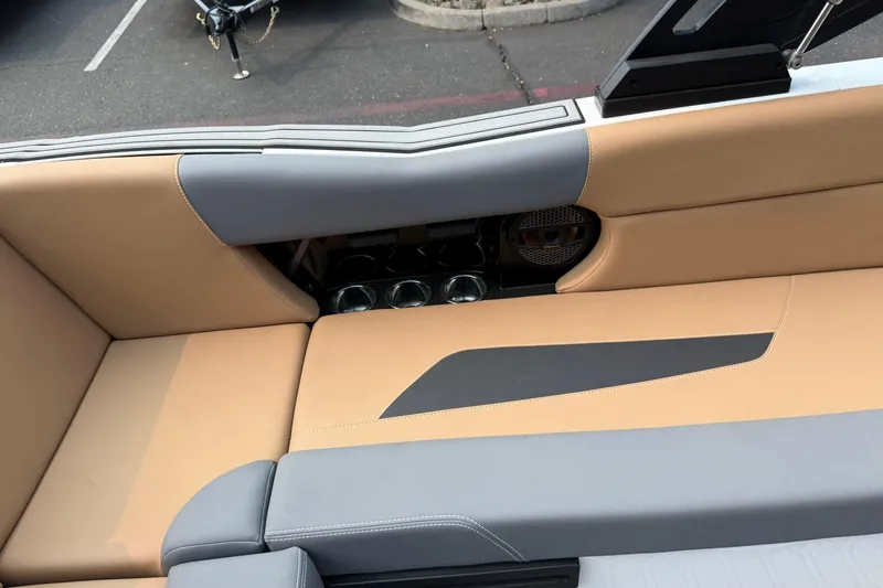 Slide: The Image of 2024 MasterCraft NXT23 boat interior with tan and gray seating, cup holders, and speaker. - 20
