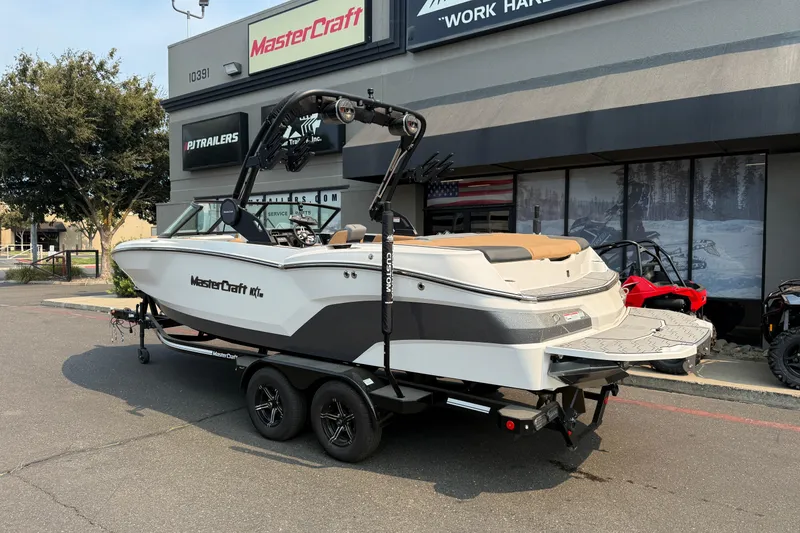 Slide: The Image of 2024 MasterCraft NXT23 boat on trailer outside dealership. - 3