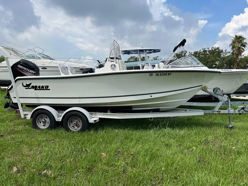 Slide: The Image of 2015 Mako 184 CC boat on trailer, parked on grass under a cloudy sky. - 2
