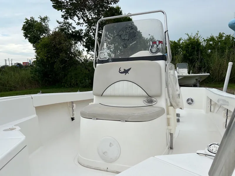 Slide: The Image of 2015 Mako 184 CC boat with center console and cushioned seating, surrounded by greenery. - 6