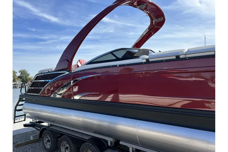Slide: The Image of 2023 Bennington QX Sport 25 pontoon boat with sleek red design on trailer. - 2