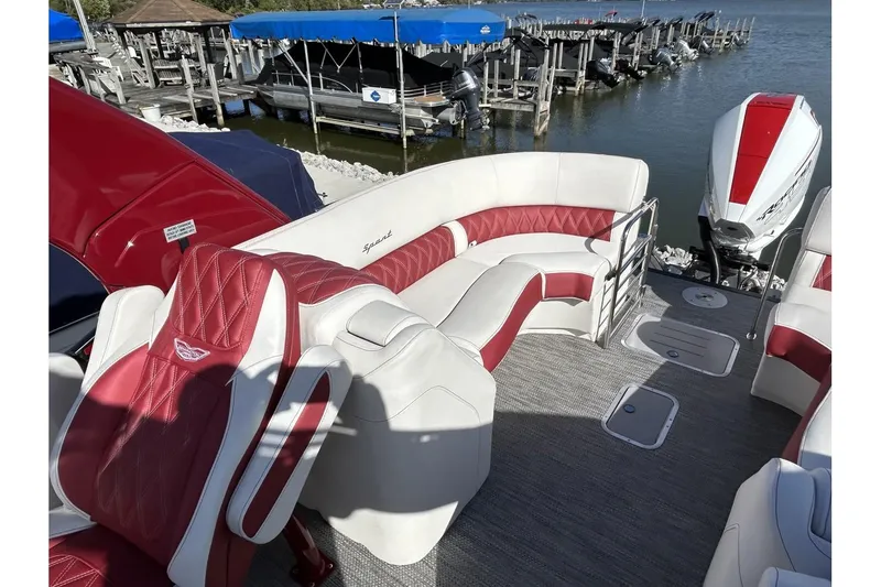 Slide: The Image of 2023 Bennington QX Sport 25 pontoon boat with red and white seating, docked by a marina. - 4
