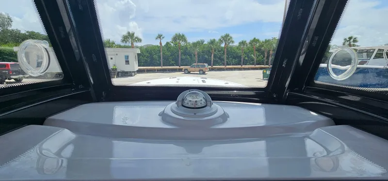 Slide: The Image of 2023 Tidewater 232 LXF boat dashboard with compass, docked under clear sky. - 20