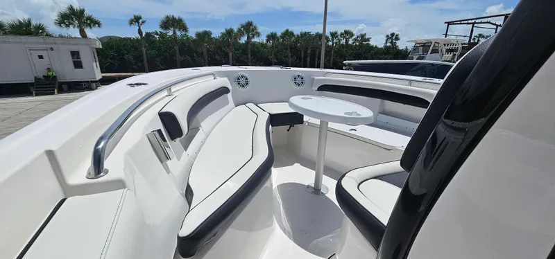 Slide: The Image of 2023 Tidewater 232 LXF boat interior with seating and table, surrounded by palm trees. - 23