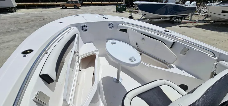 Slide: The Image of 2023 Tidewater 232 LXF boat interior with seating and table, docked outdoors. - 26