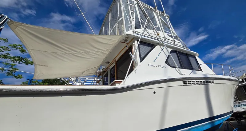 Slide: The Image of 1989 Chris-Craft 392 Commander boat with canopy, docked under a clear blue sky. - 3