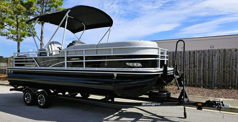 Slide: The Image of 2024 Ranger Reata 220FC pontoon boat on trailer, parked outdoors. - 2