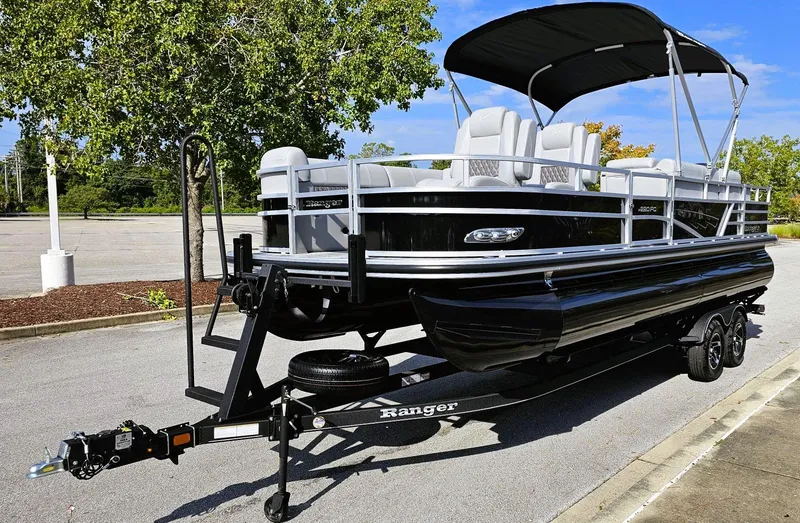 Slide: The Image of 2024 Ranger Reata 220FC pontoon boat on trailer, parked outdoors. - 7