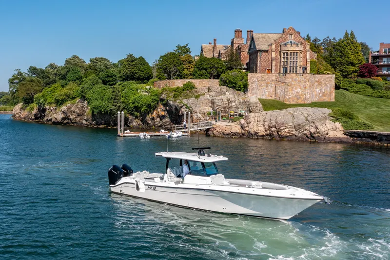 Slide: The Image of 2024 HCB 39 Speciale boat cruising near a historic mansion on a rocky shoreline. - 3