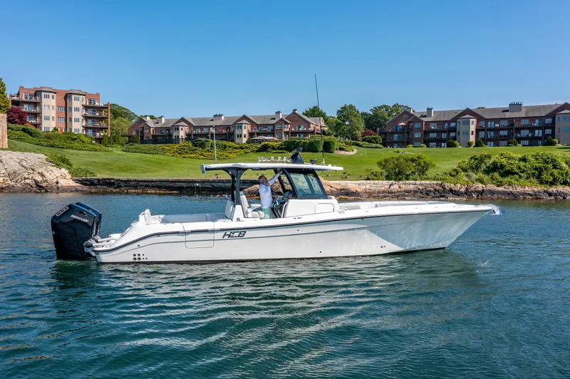 Slide: The Image of 2024 HCB 39 Speciale boat cruising near a scenic shoreline with buildings in the background. - 41