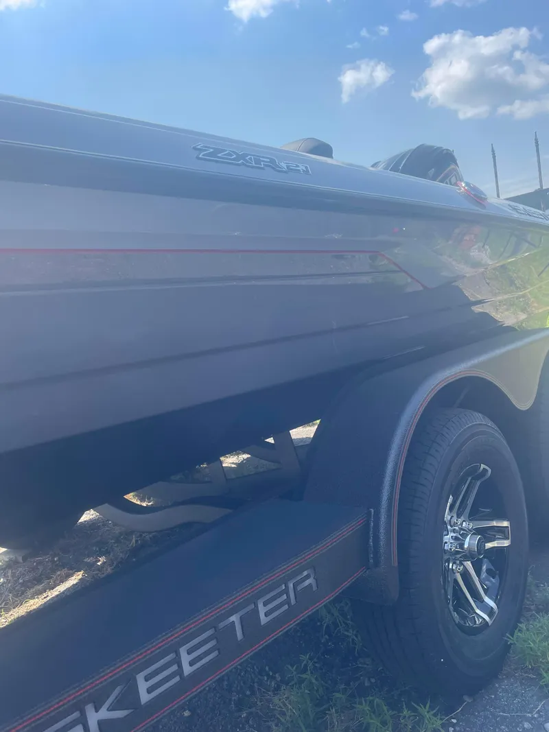 Slide: The Image of 2025 Skeeter ZXR21 boat on trailer under a blue sky. - 8