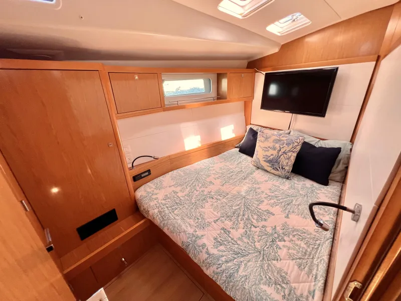 Slide: The Image of 2012 Beneteau Sense 50 yacht bedroom with double bed, TV, and wooden cabinetry. - 11