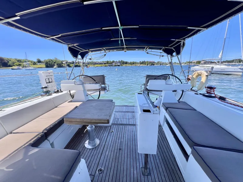 Slide: The Image of 2012 Beneteau Sense 50 sailboat cockpit with seating and table, docked in a scenic marina. - 15