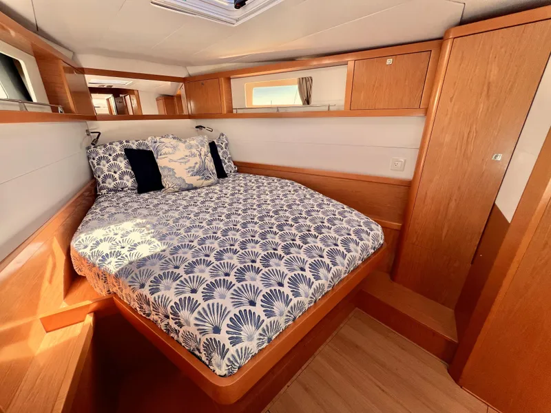 Slide: The Image of 2012 Beneteau Sense 50 yacht bedroom with wooden interior and patterned bedding. - 8