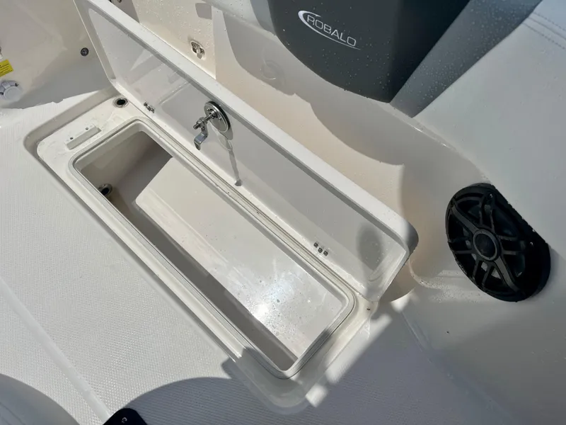 Slide: The Image of 2025 Robalo R250 boat storage compartment with open lid and built-in speaker. - 14