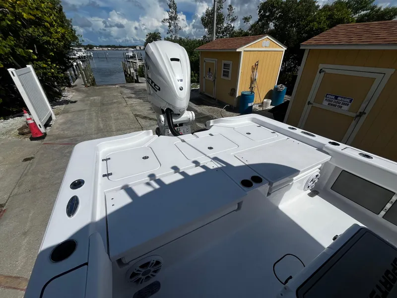 Slide: The Image of 2024 Sportsman Masters 267 Bay Boat docked, showcasing spacious deck and powerful outboard motor. - 10