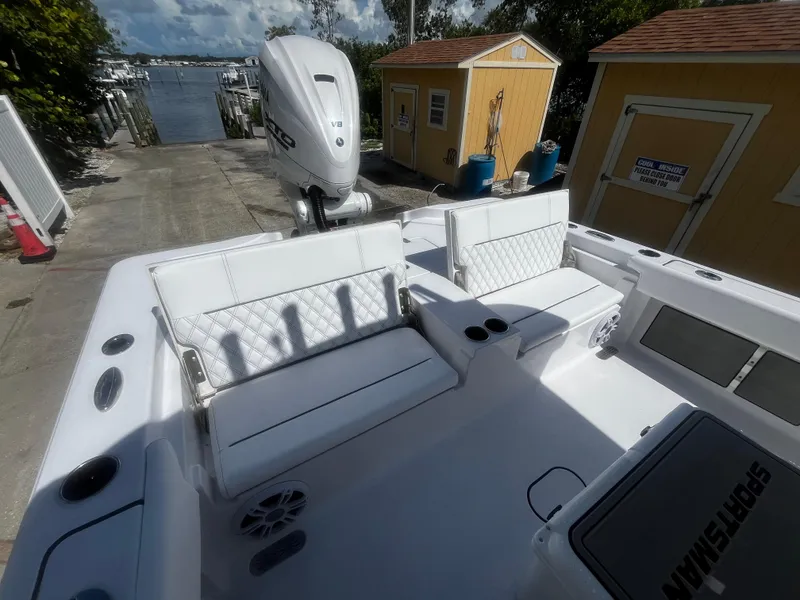 Slide: The Image of 2024 Sportsman Masters 267 Bay Boat with white seating and outboard motor at dock. - 11