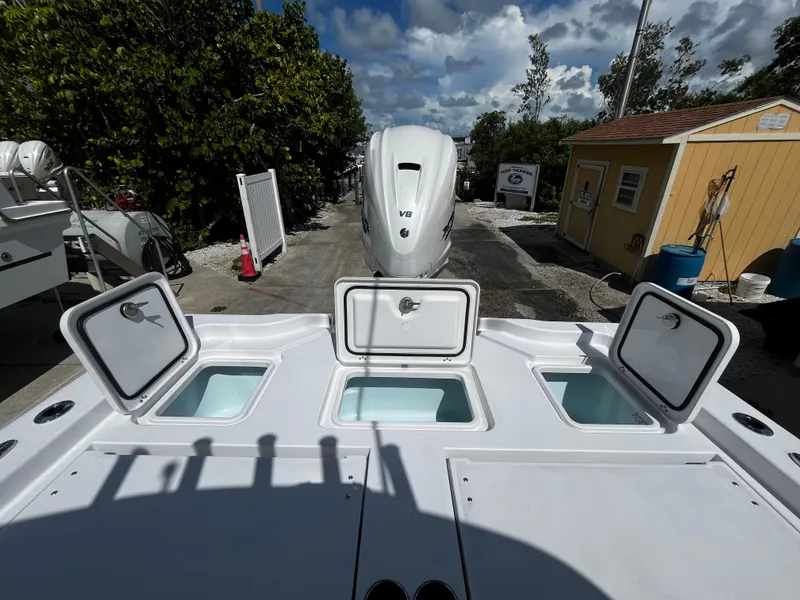 Slide: The Image of 2024 Sportsman Masters 267 Bay Boat with open storage compartments and outboard motor. - 12