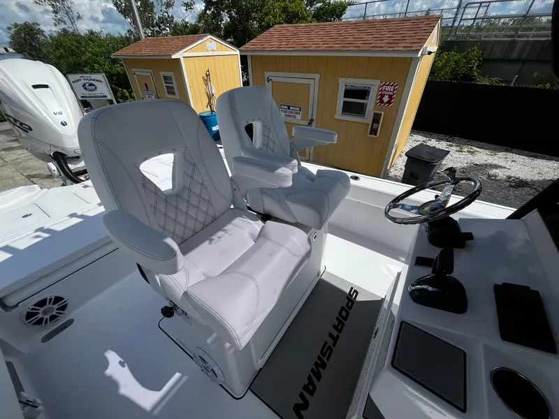 Slide: The Image of 2024 Sportsman Masters 267 Bay Boat cockpit with dual white captain's chairs and control console. - 15