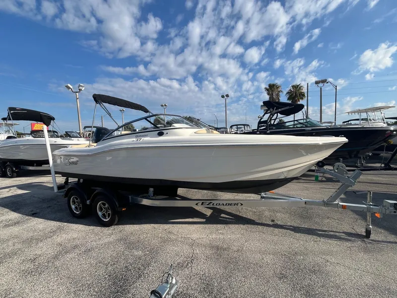 The Image of 2021 Scout 210 Dorado boat on trailer in marina under blue sky. - 0