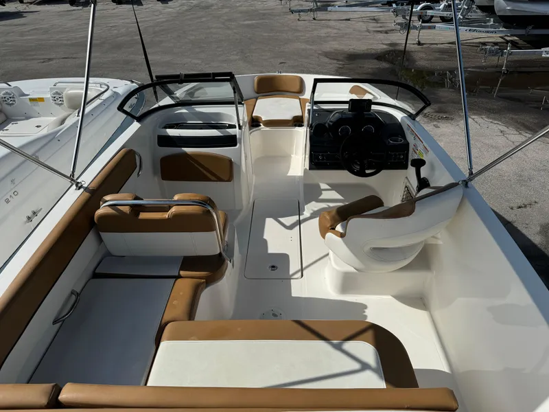 Slide: The Image of 2021 Bayliner VR5 Bowrider OB interior with tan and white seating, steering console, and open deck. - 6