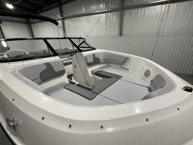 Slide: The Image of 2024 Bayliner VR5 Bowrider boat interior with gray and white seating in a warehouse. - 10
