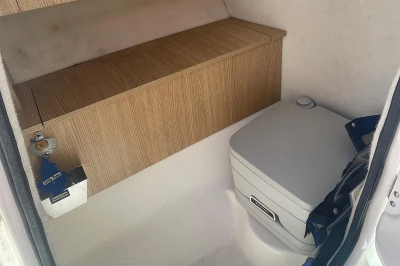 Slide: The Image of 2015 Robalo R227 Dual Console boat interior with compact toilet and storage. - 6