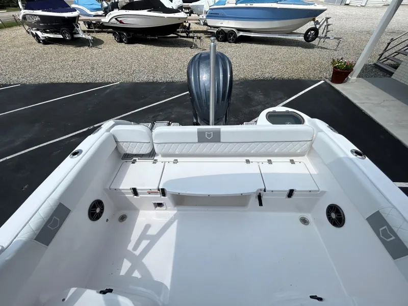 Slide: The Image of 2025 Sea Fox 228 Traveler boat interior with seating and motor, parked on gravel. - 17