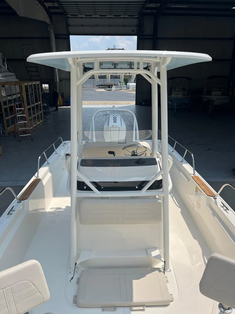 Slide: The Image of 2024 Boston Whaler 210 Montauk boat interior with T-top in a warehouse. - 2